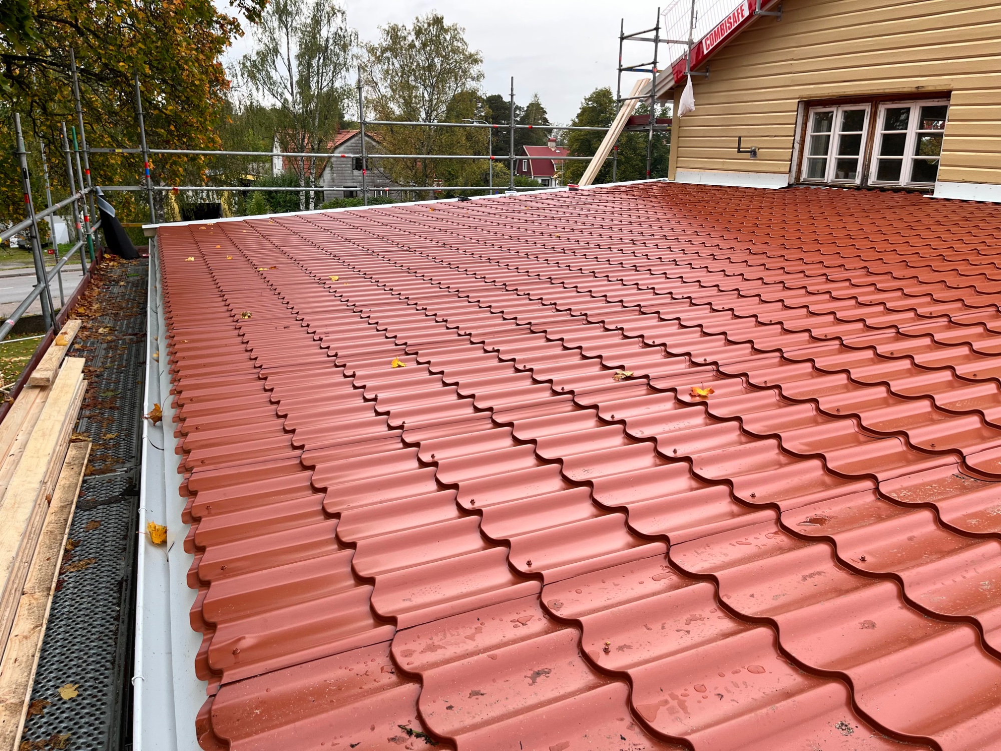 Nylagt rødt takplatetak med stillas rundt bygget